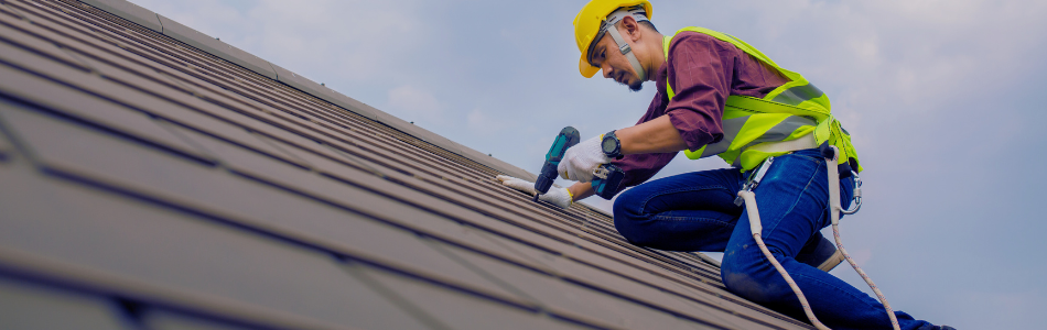 Construction worker on a roof drilling